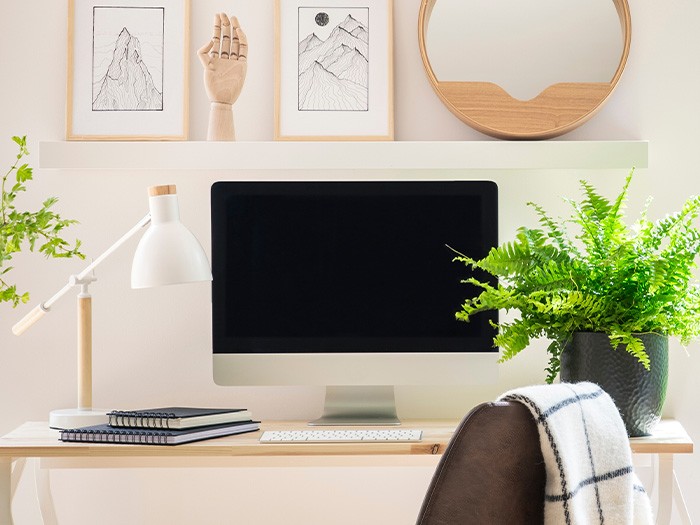 Work station featuring modern style desk, computer monitor, and modern lamp.